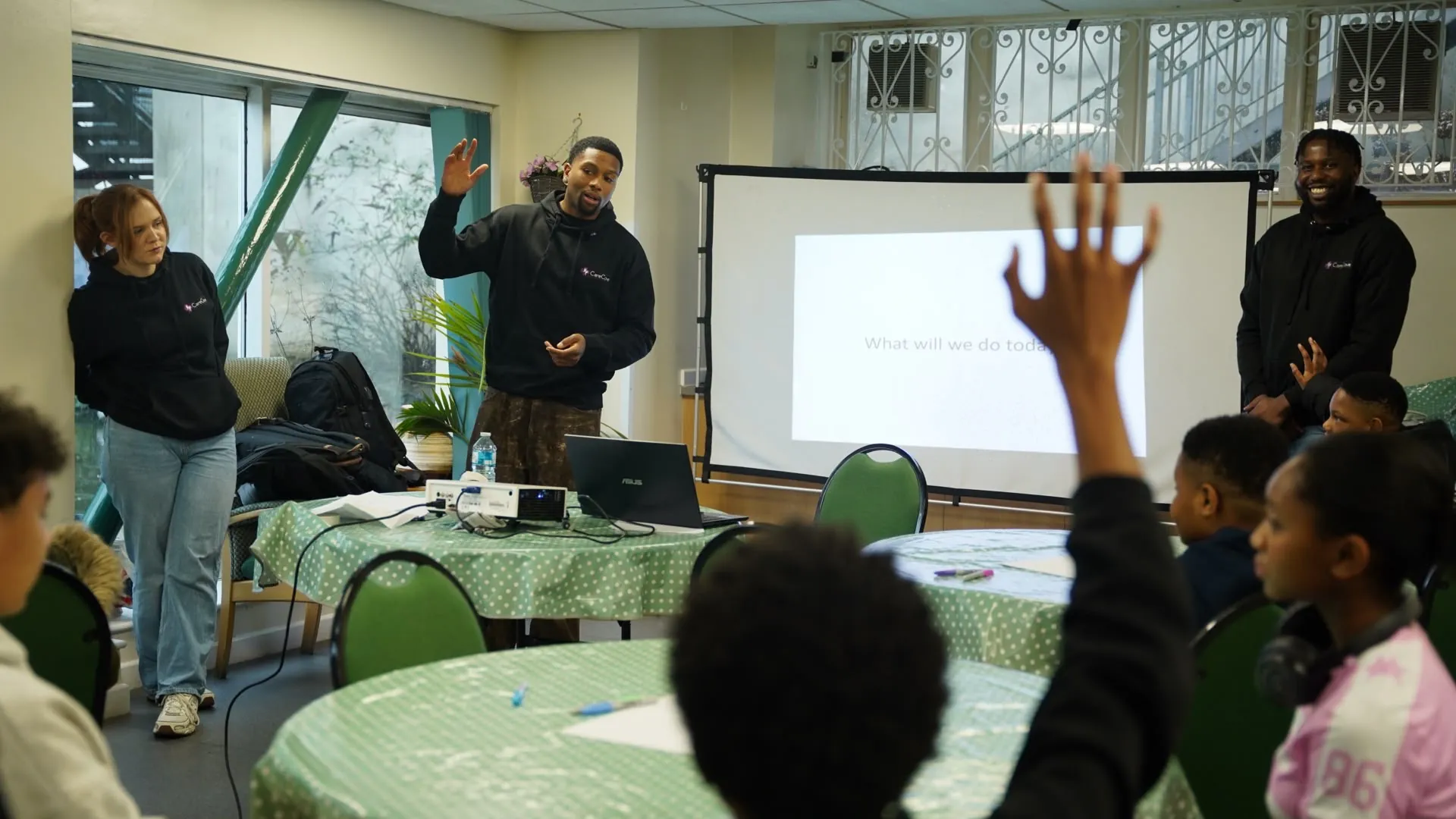 Care Cove staff leading a group session while a young person raises their hand